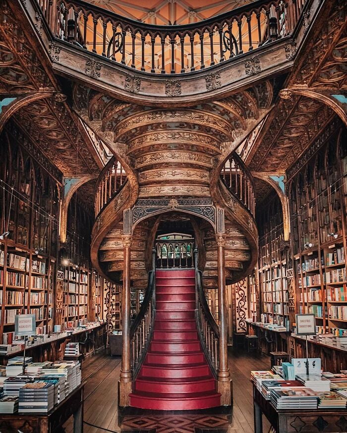 Libreria sfarzosa e imponente con una scalinata a chiocciola intagliata in legno e file di scaffali pieni di libri tutt'intorno. Libreria sfarzosa e imponente con una scalinata a chiocciola intagliata in legno e file di scaffali pieni di libri tutt'intorno.