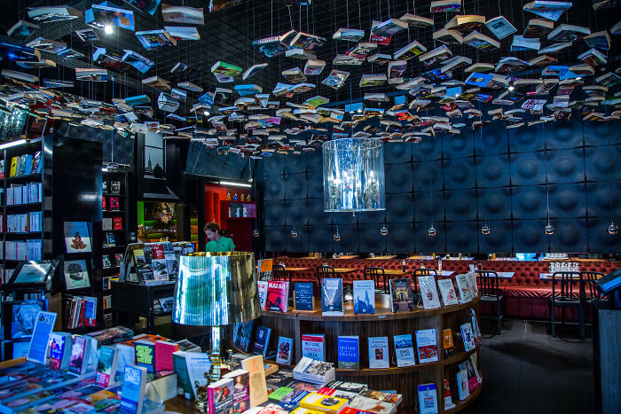 Interior of a grandiose bookstore with books hanging from the ceiling and cozy seating in a magical atmosphere. Interior of a grandiose bookstore with books hanging from the ceiling and cozy seating in a magical atmosphere.